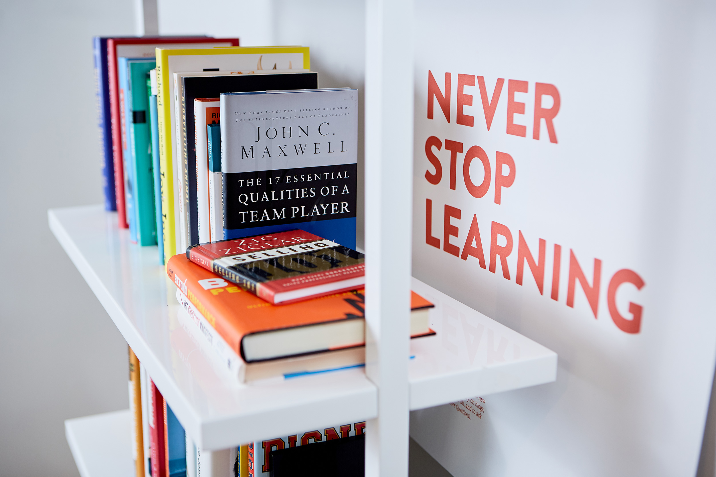 Photo of books on a shelf with a nearby poster that reads Never Stop Learning